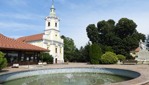 Templomot látunk, előtte egy közterületi szökőkút medencéjével, Letenye városának központjában.